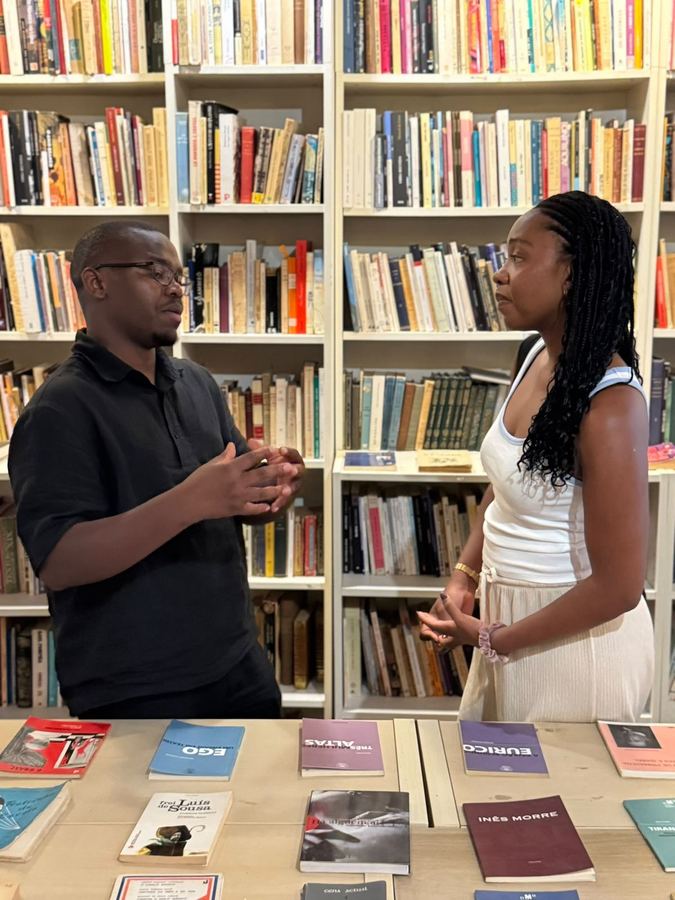 Two members in conversation in front of a bookshelf